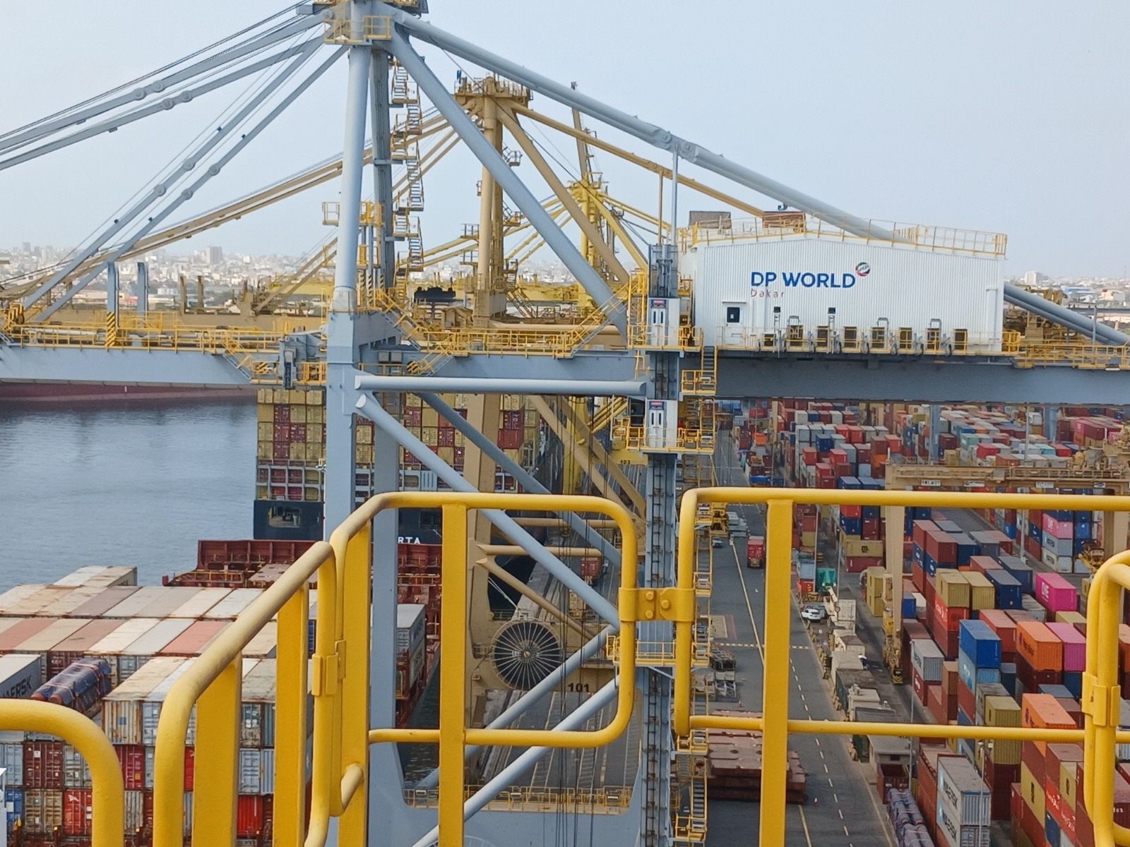 Ship-to-shore crane seen from a walkway, with the rope drum and container stacks